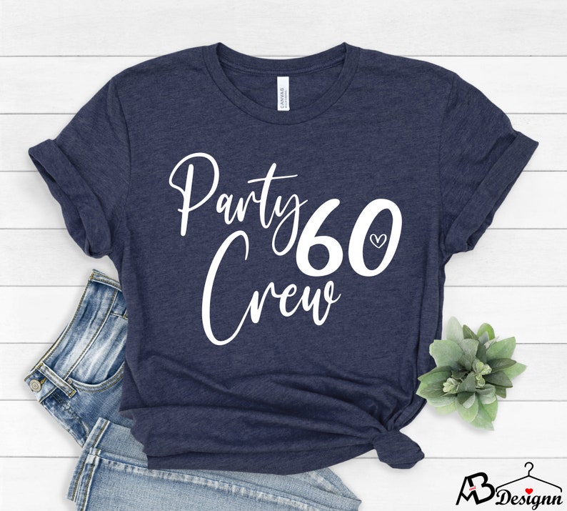 May include: A navy blue t-shirt with white text that says "Party Crew 60" with a small heart symbol next to the number 60.