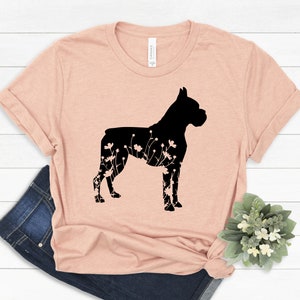K&ouml;nnte beinhalten: Ein hellrosa T-Shirt mit einer schwarzen Silhouette eines Boxerhundes mit floralen Details innerhalb der Silhouette.