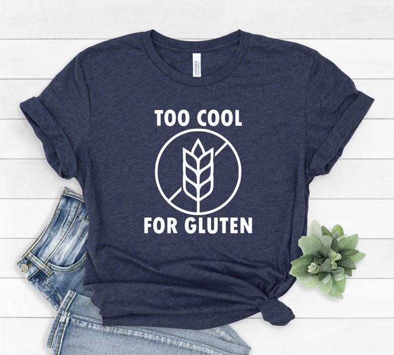 May include: A navy blue t-shirt with white text that reads "Too Cool For Gluten" and a white graphic of a wheat stalk with a diagonal line through it.