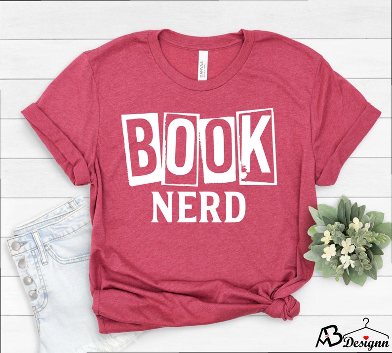 Może przedstawiać: Czerwony T-shirt z nadrukiem "BOOK NERD" w kolorze białym z przodu.