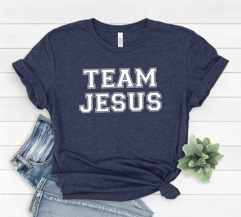 May include: A navy blue t-shirt with white text that reads "TEAM JESUS" in a collegiate font.