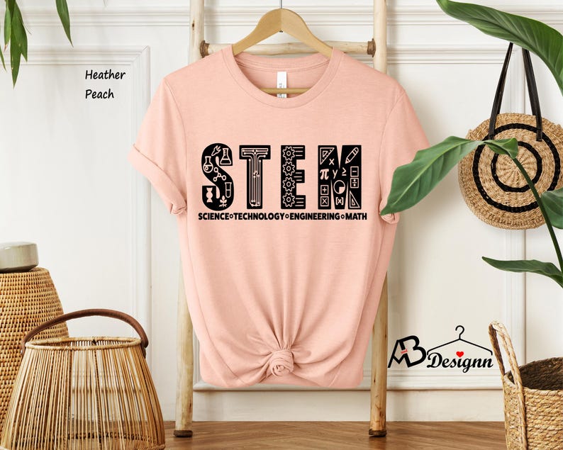 May include: A peach colored t-shirt with a black graphic that says "STEM" with icons representing science, technology, engineering, and math. The text below the graphic says "SCIENCE-TECHNOLOGY-ENGINEERING-MATH".