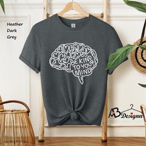 May include: Dark heather grey t-shirt with a white outline of a brain with the text "Be Kind To Your Mind" inside.