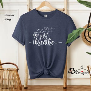 May include: A navy blue t-shirt with a white dandelion graphic and the text "just breathe".