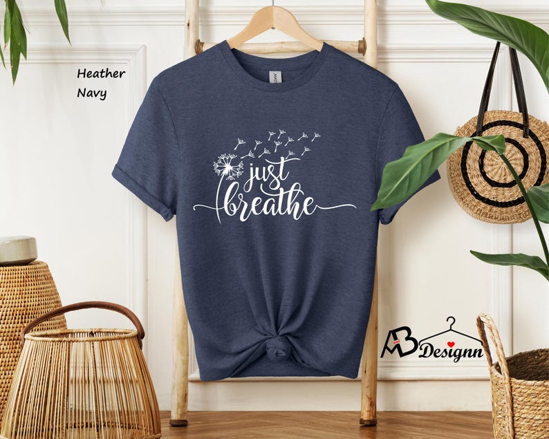 May include: A navy blue t-shirt with a white dandelion graphic and the text "just breathe".
