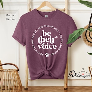 May include: Heather maroon t-shirt with the text "be their voice" in a circular design. The design includes a paw print and the phrases "Rescue the mistreated, save the injured, love the abandoned". The shirt is knotted at the waist.