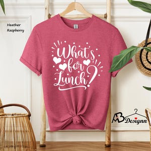 K&ouml;nnte beinhalten: Ein T-Shirt in der Farbe Heide-Himbeere mit dem Text "What's for lunch?" in wei&szlig;en Buchstaben mit drei wei&szlig;en Herzen.