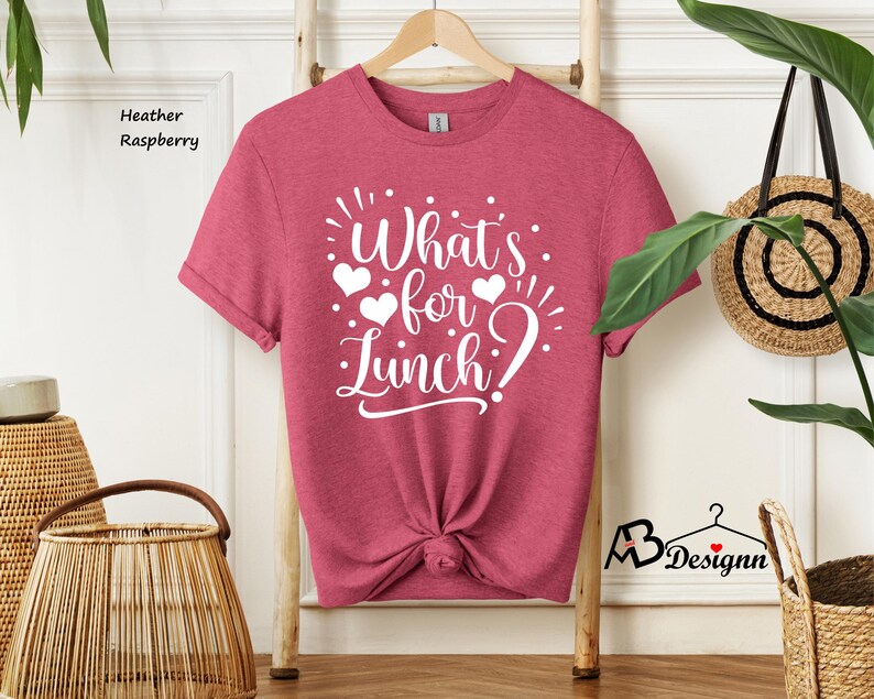 K&ouml;nnte beinhalten: Ein T-Shirt in der Farbe Heide-Himbeere mit dem Text "What's for lunch?" in wei&szlig;en Buchstaben mit drei wei&szlig;en Herzen.