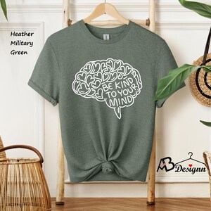 May include: A green t-shirt with a white outline of a brain with the text "Be Kind To Your Mind" inside. The brain is made up of hearts.