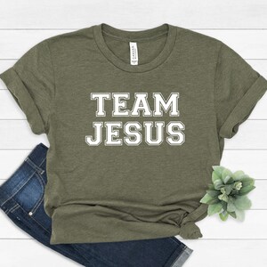 May include: A green t-shirt with the text "TEAM JESUS" in white block letters.