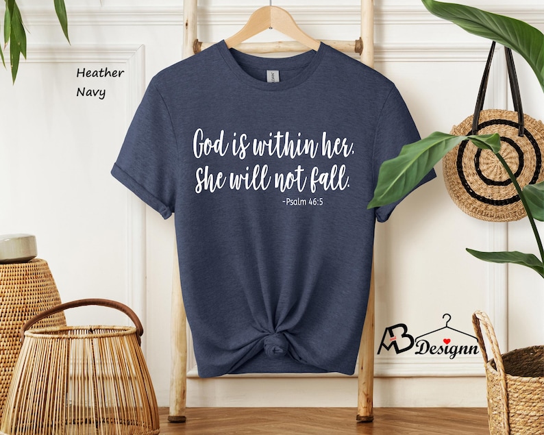Peut inclure: Un t-shirt bleu marine avec le texte "Dieu est en elle. Elle ne tombera pas. -Psaume 46:5" imprim&eacute; en blanc.