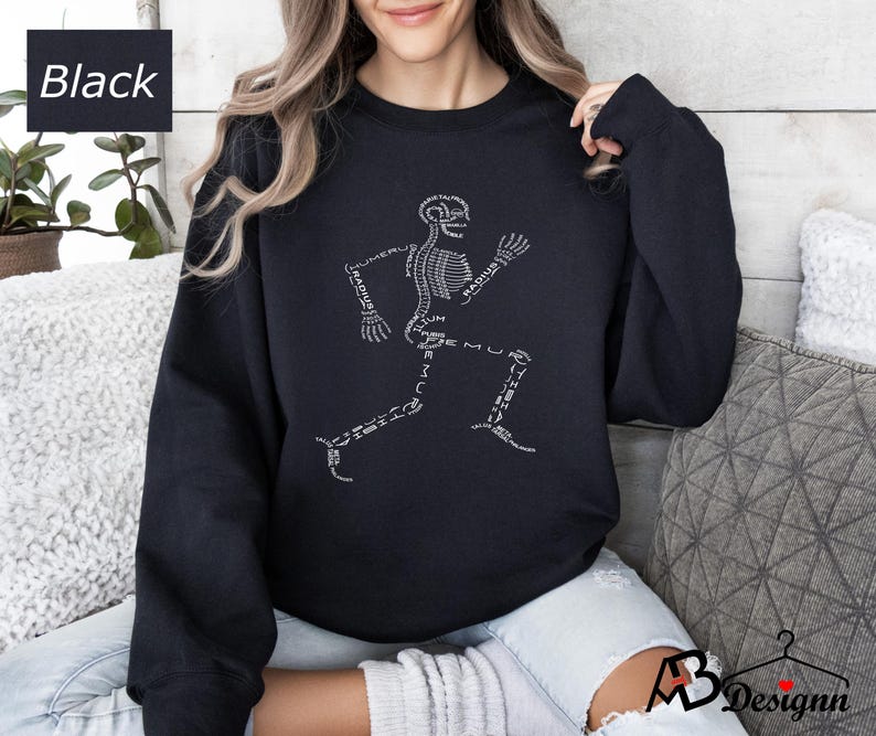 Peut inclure: Sweat-shirt noir avec un motif de coureur squelettique blanc et des &eacute;tiquettes d'os. Le mot "Black" est dans un encadr&eacute; blanc en haut &agrave; gauche. Un style de sweat-shirt confortable et d&eacute;contract&eacute;.