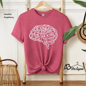 May include: Heather raspberry colored t-shirt with a white outline of a brain with hearts inside and the text "Be Kind To Your Mind".