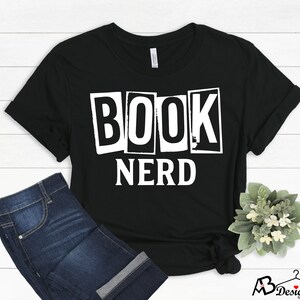 Może przedstawiać: Czarny T-shirt z białym tekstem, kt&oacute;ry brzmi "BOOK NERD" w stylu vintage.