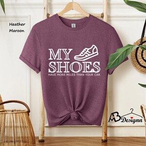 May include: Heather maroon t-shirt with a white graphic of a running shoe and the text "My Shoes Have More Miles Than Your Car."