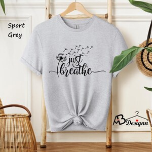 May include: A heather grey t-shirt with a dandelion graphic and the text "just breathe".