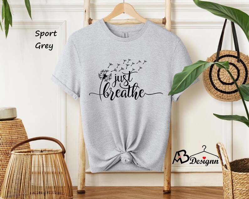 May include: A heather grey t-shirt with a dandelion graphic and the text "just breathe".