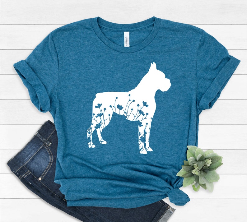 K&ouml;nnte beinhalten: Ein blaues T-Shirt mit einer wei&szlig;en Silhouette eines Boxerhundes mit Blumen in der Silhouette.