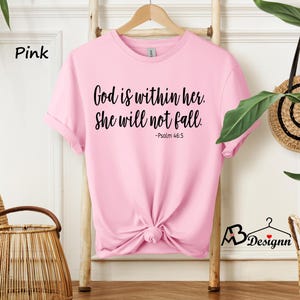 Peut inclure: T-shirt rose avec le texte "God is within her. She will not fall. -Psalm 46:5" imprim&eacute; en noir.