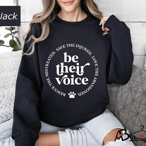 May include: Black sweatshirt with a white circle graphic that says "Be their voice" with a paw print in the center. The circle also says "Rescue the mistreated, save the injured, love the abandoned".