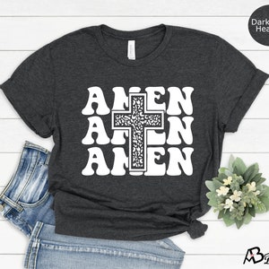 May include: Dark grey heather t-shirt with a white graphic of a cross and the word "Amen" repeated three times.