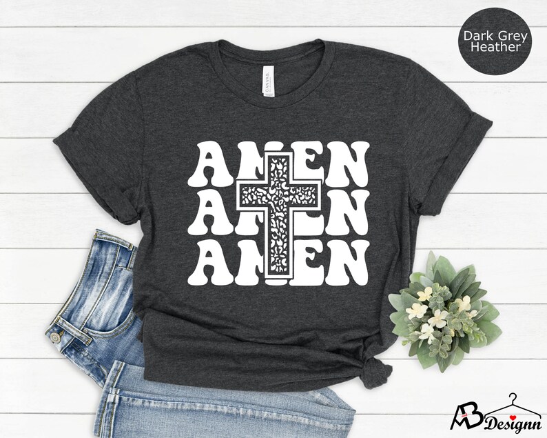 May include: Dark grey heather t-shirt with a white graphic of a cross and the word "Amen" repeated three times.