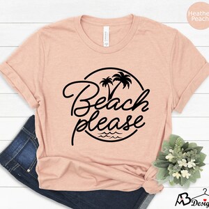 Może przedstawiać: Koszulka w kolorze brzoskwiniowym z nadrukiem czarnych palm i napisem "Beach Please" w k&oacute;łku.