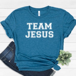 May include: A teal blue t-shirt with the text "TEAM JESUS" in white block letters.