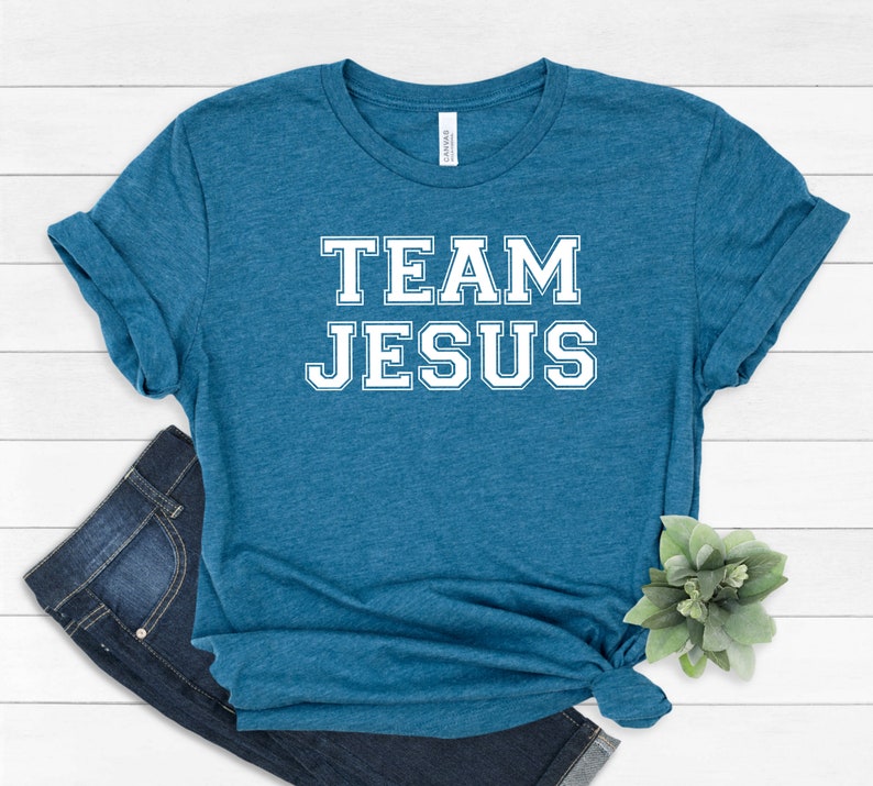May include: A teal blue t-shirt with the text "TEAM JESUS" in white block letters.