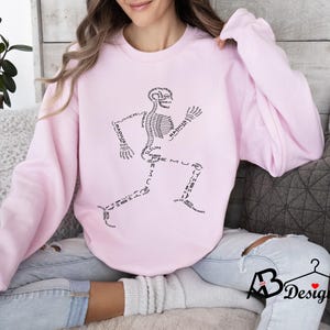Peut inclure: Sweat-shirt rose clair avec un motif de coureur squelettique noir. Les os sont &eacute;tiquet&eacute;s avec des termes anatomiques. Le sweat-shirt a des manches longues et un col rond. Le motif est centr&eacute; sur le devant.