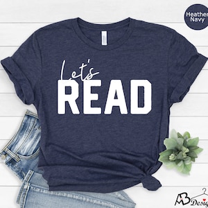May include: A heather navy blue t-shirt with the text "Let's Read" in white.