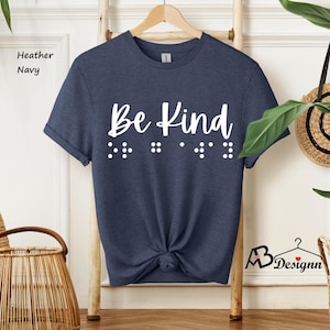 May include: A heather navy blue t-shirt with the text "Be Kind" in white lettering and braille dots below the text.