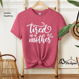 May include: A heather raspberry t-shirt with the text "Tired as a mother" in white lettering.