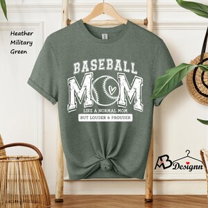 May include: A heather military green t-shirt with the text "BASEBALL MOM" in white. The text is surrounded by a baseball graphic and the words "Like a normal mom but louder & prouder".