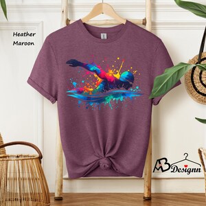 May include: Heather maroon t-shirt with a colorful graphic of a swimmer in a splash of water.