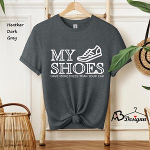 May include: Dark heather grey t-shirt with a white graphic of a sneaker and the text "My Shoes Have More Miles Than Your Car."
