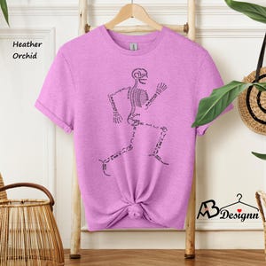 May include: A heather orchid t-shirt with a skeleton graphic. The skeleton is running and the bones are labeled with their anatomical names.