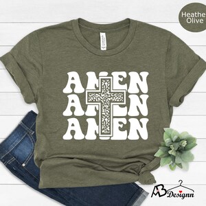 May include: A green t-shirt with a white graphic of the word "Amen" repeated three times with a cross in the center. The cross is filled with a floral pattern.