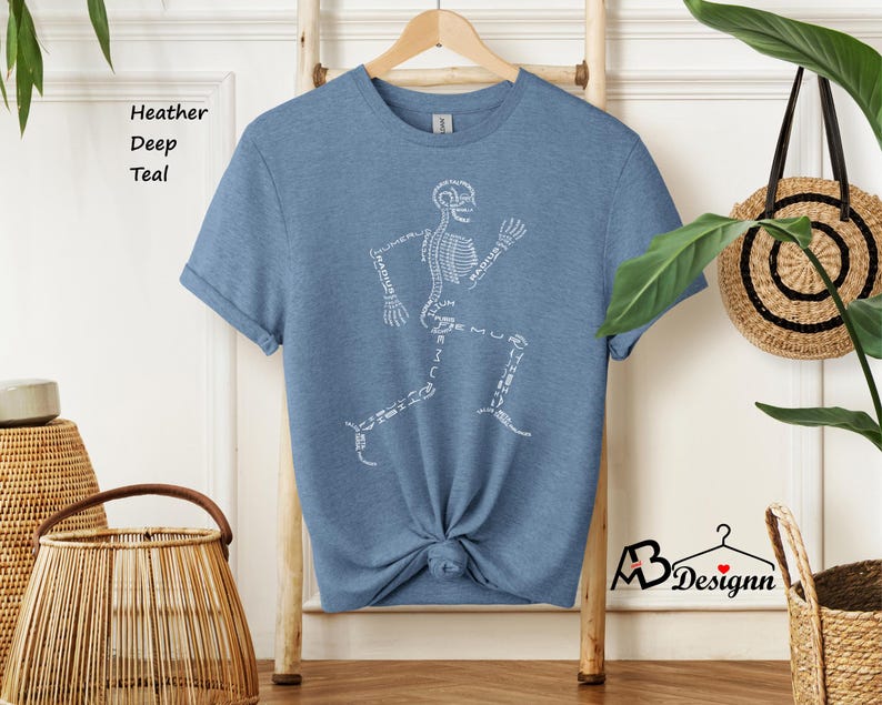 May include: A heather deep teal t-shirt with a white skeleton running design. The skeleton is made up of the names of bones.