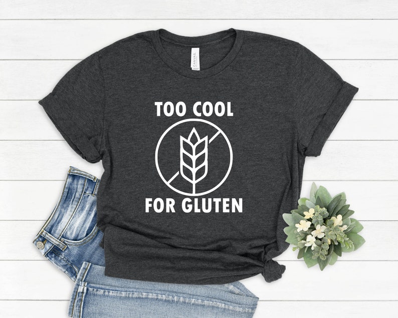 May include: A dark gray t-shirt with white text that reads "Too Cool For Gluten" and a white graphic of a wheat stalk with a diagonal line through it.