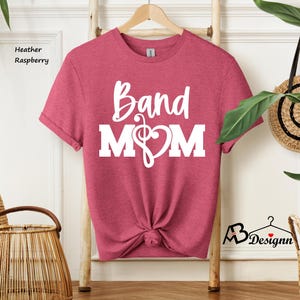 May include: A heather raspberry t-shirt with the text "Band Mom" in white. The text includes a treble clef and a heart.