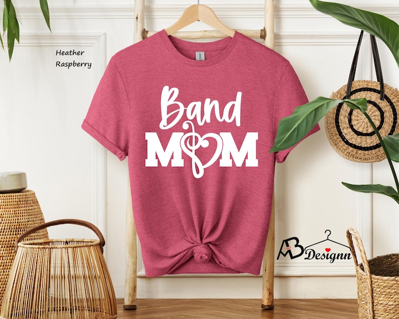 May include: A heather raspberry t-shirt with the text "Band Mom" in white. The text includes a treble clef and a heart.