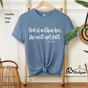 Peut inclure: Un t-shirt bleu sarcelle fonc&eacute; chin&eacute; avec le texte "God is within her. She will not fall. -Psalm 46:5" imprim&eacute; en blanc.