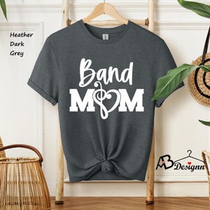 May include: Dark heather grey t-shirt with white text that reads "Band Mom" and a musical note with a heart.