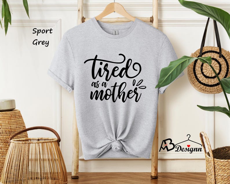 May include: A light grey t-shirt with the text "tired as a mother" in black lettering.