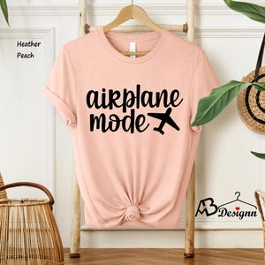 May include: A peach colored t-shirt with the text "airplane mode" in black lettering and a small airplane icon.