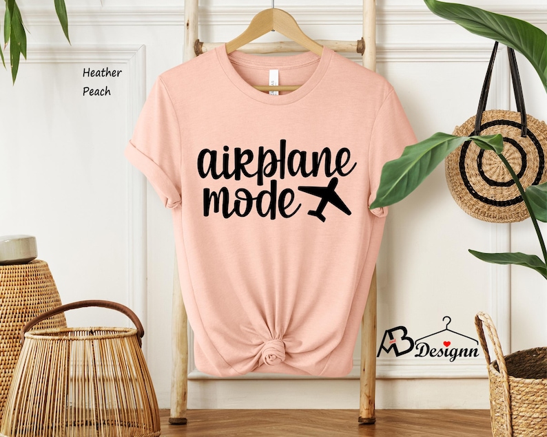 May include: A peach colored t-shirt with the text "airplane mode" in black lettering and a small airplane icon.