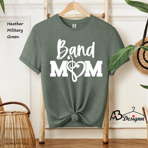 May include: A heather military green t-shirt with the text "Band Mom" in white lettering. A musical note and heart are included in the design.