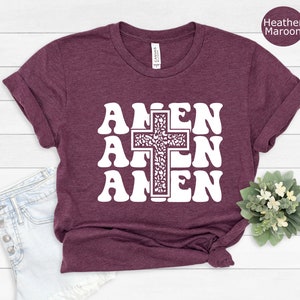 May include: A heather maroon t-shirt with a white graphic of the word "AMEN" repeated three times with a cross in the center.
