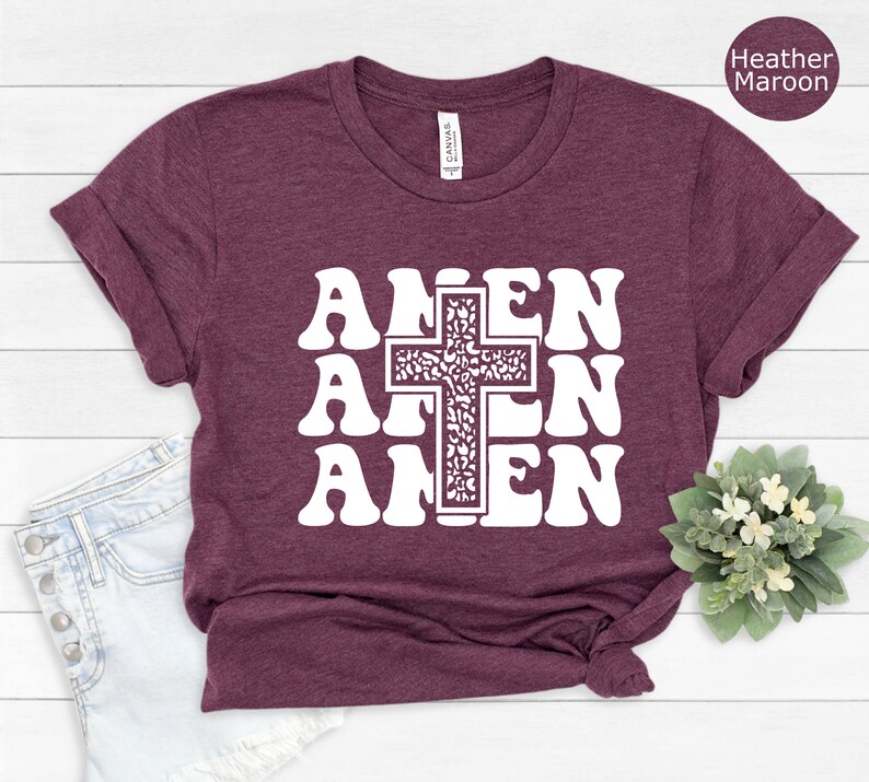 May include: A heather maroon t-shirt with a white graphic of the word "AMEN" repeated three times with a cross in the center.